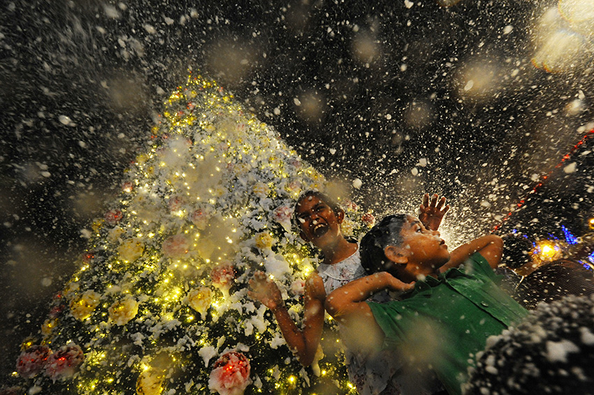 12月24日,在新加坡乌节路,两名儿童在一家购物中心感受人造雪.